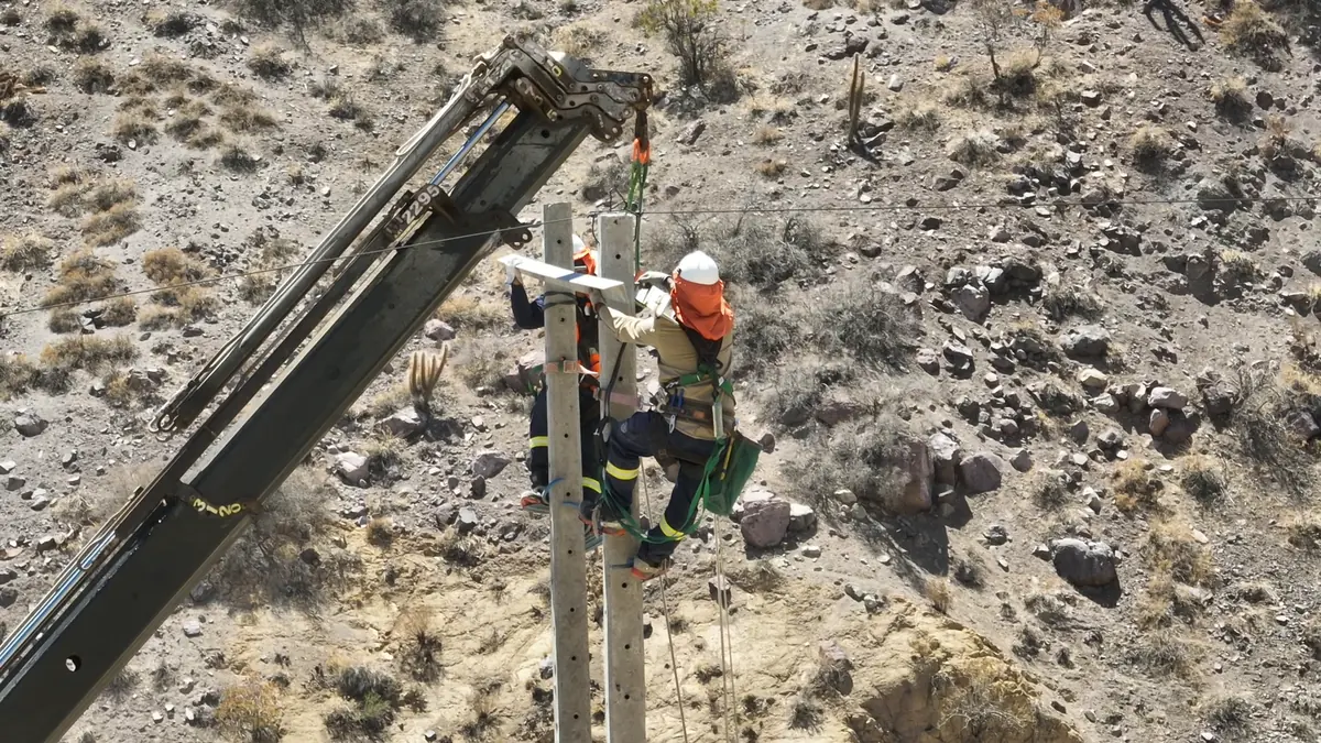 Liniero con arnés trabajando en altura durante el reemplazo de un portal eléctrico